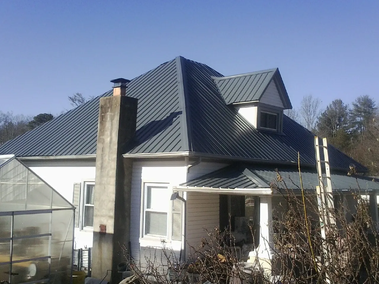 Dark blue standing seam metal roof on a white farmhouse with dormer — Slate & Tile Roof Repair by Roofing Brothers in Clairfield