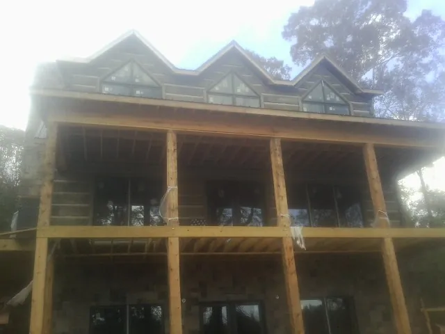 Dormers and porch framing on a large log home under construction — Roof Coating work by our crew in Clairfield