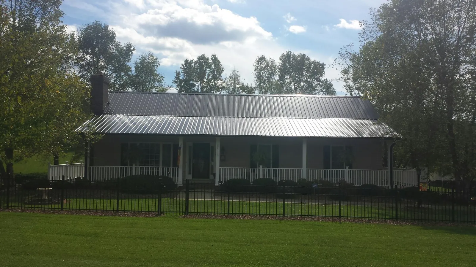 Gray metal roof on a brick ranch with a full width front porch — Gutter Guard Installation work by our crew in Clairfield